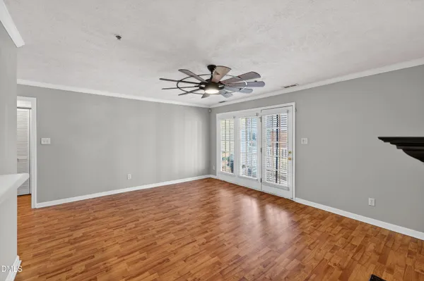 a view of an empty room with wooden floor and a window