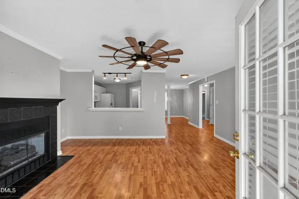 a view of an empty room with chandelier fan and fire place