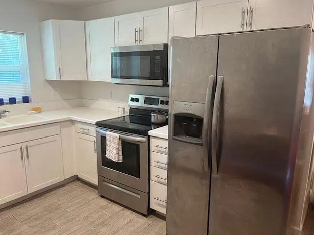 a kitchen with a refrigerator stove and white cabinets