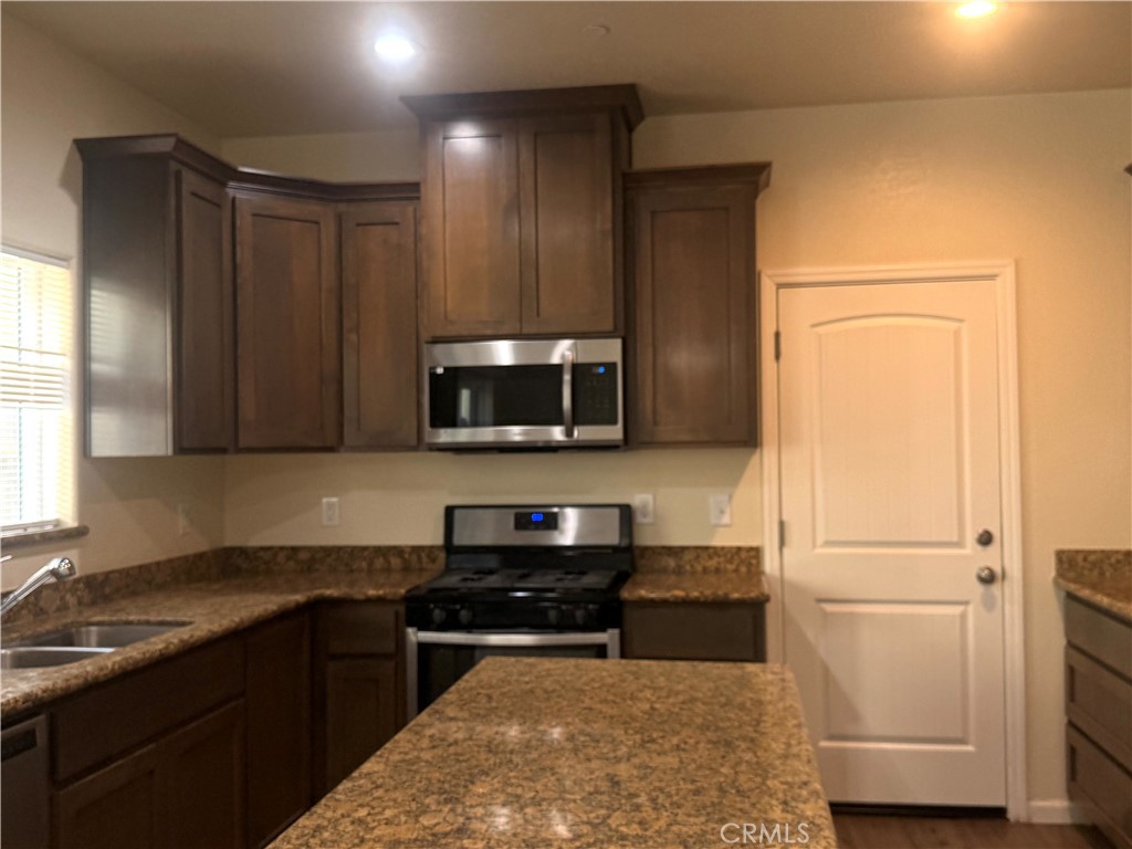 1339 Playa Del Rey Drive Merced, CA 95348 - Photo 8 of 48 a kitchen with stainless steel appliances granite countertop a refrigerator a sink a stove a microwave and wooden cabinets