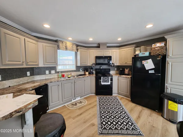a kitchen with a refrigerator a sink dishwasher a stove and white cabinets with wooden floor