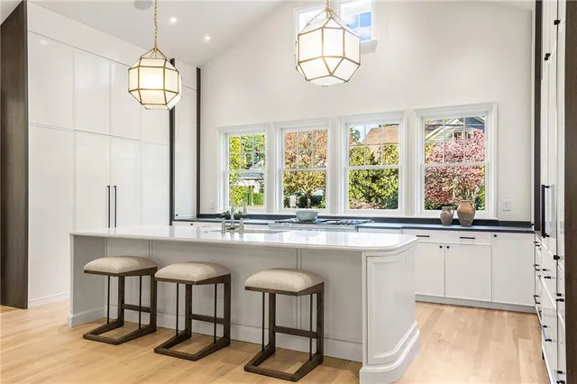 a kitchen with stainless steel appliances granite countertop a stove a sink dishwasher a dining table and chairs with wooden floor