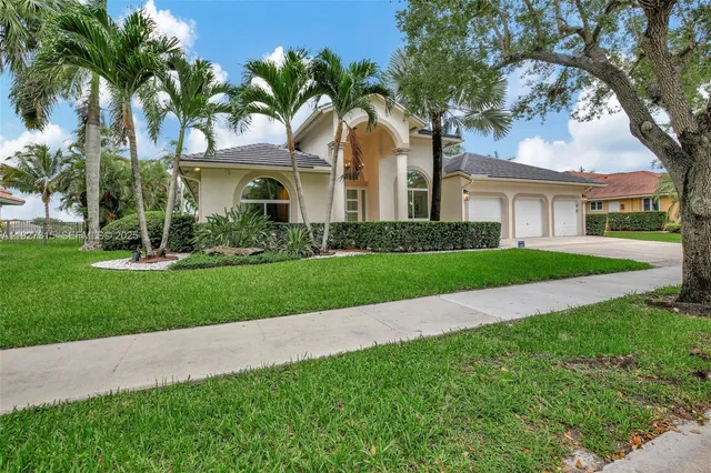 a view of a white house with a big yard and palm trees
