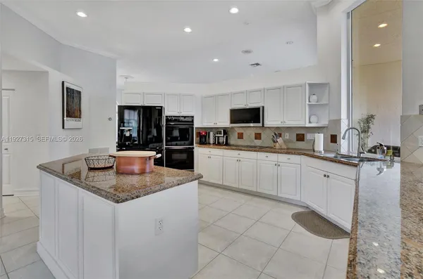 a kitchen with stainless steel appliances granite countertop a refrigerator a sink a stove and white cabinets