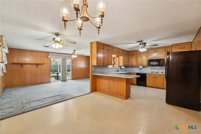 a large kitchen with stainless steel appliances granite countertop a refrigerator a oven and a sink with granite countertops