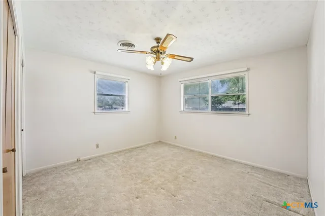 an empty room with a window and ceiling fan