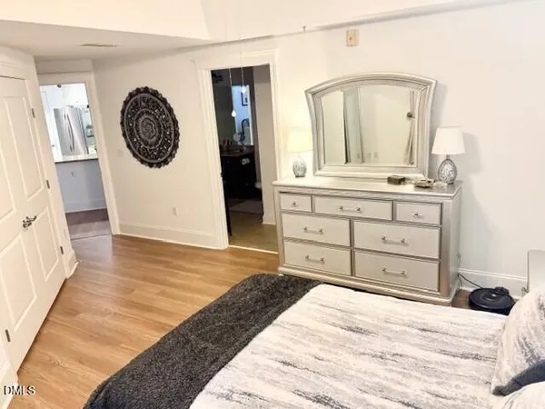 a bedroom with a bed a mirror on dresser and a window