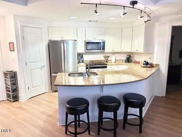 a kitchen with stainless steel appliances granite countertop a table chairs microwave and refrigerator