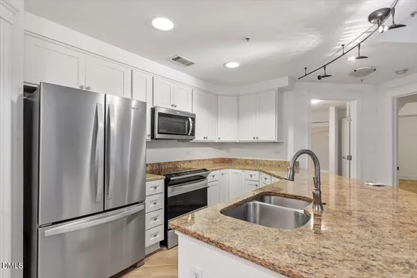 a kitchen with granite countertop a refrigerator and a sink