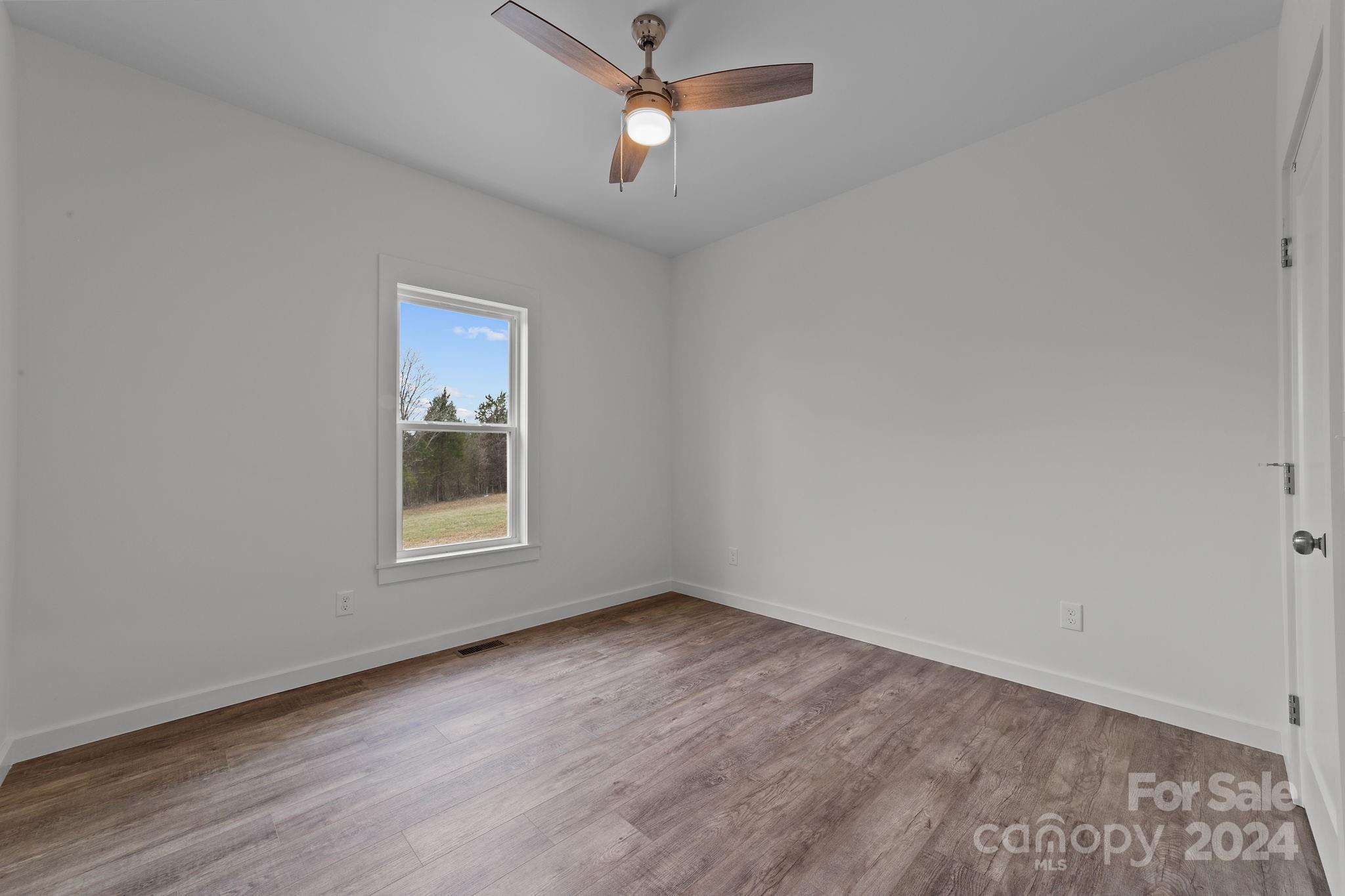 220 Linker Road Rockwell, NC 28138 - Photo 30 of 48 an empty room with wooden floor ceiling fan and windows