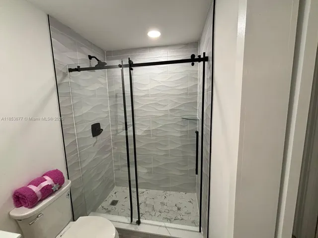 a bathroom with a granite countertop sink toilet a mirror and shower