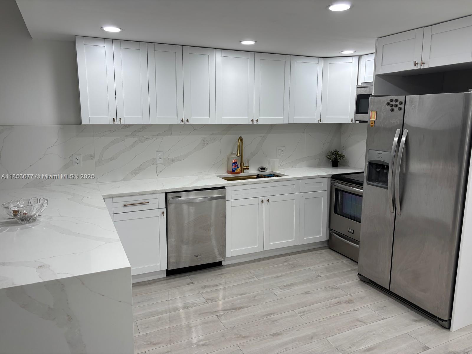6886 Northwest 166th Terrace, Unit 1004 Miami Lakes, FL 33014 - Photo 23 of 27 a kitchen with a sink a refrigerator and white cabinets