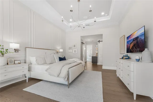a bedroom with a bed mirror on dresser and a flat screen tv