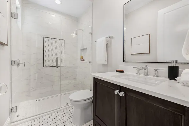 a bathroom with a granite countertop sink a toilet a mirror and shower