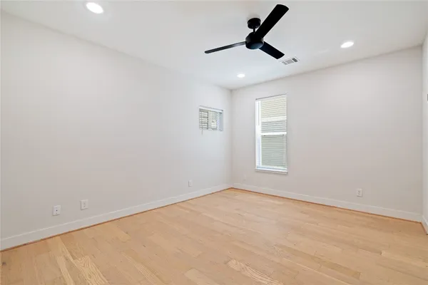 an empty room with ceiling fan and windows