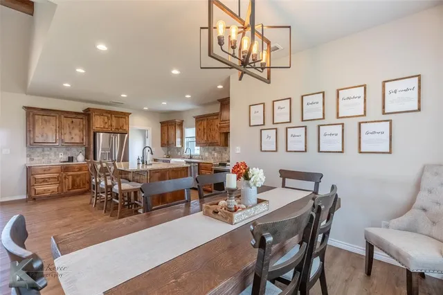 a dining room with wooden floor a chandelier a wooden table and chairs