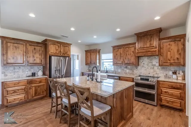 a kitchen with stainless steel appliances granite countertop a kitchen island hardwood floor sink and stove