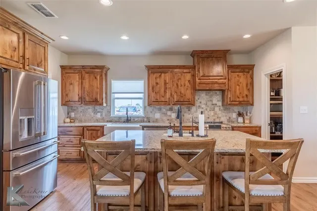 a kitchen with granite countertop a table chairs microwave and refrigerator