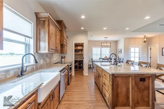 a large kitchen with kitchen island granite countertop lots of counter top space a sink a window and stainless steel appliances