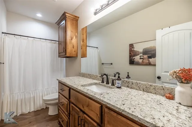 a bathroom with a granite countertop sink a toilet and a mirror