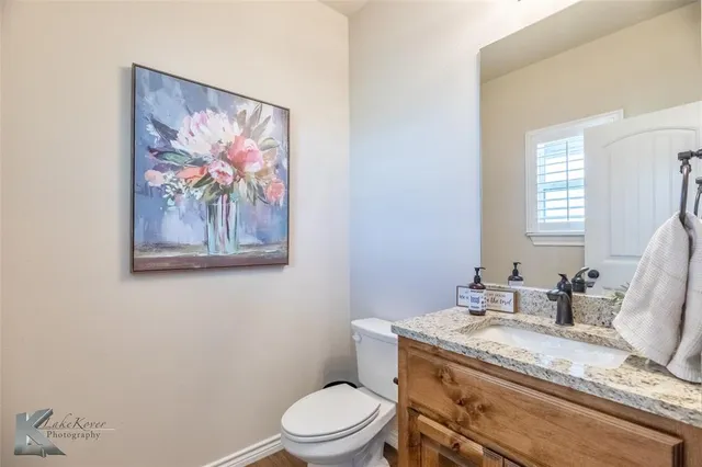 a bathroom with a granite countertop toilet a sink and mirror