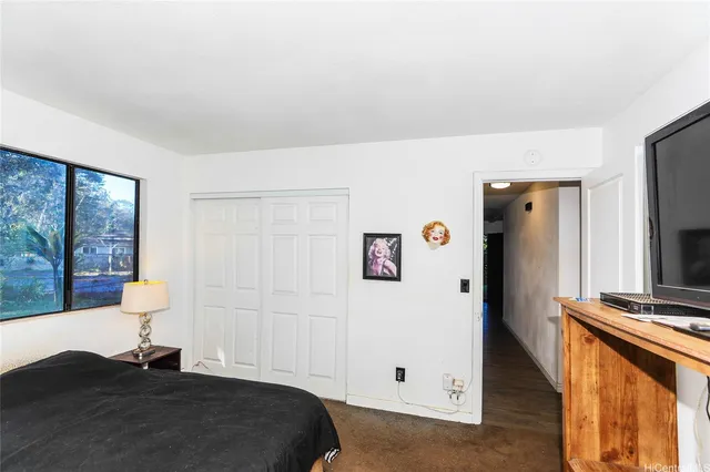 a bedroom with a bed and a flat tv screen on the dresser