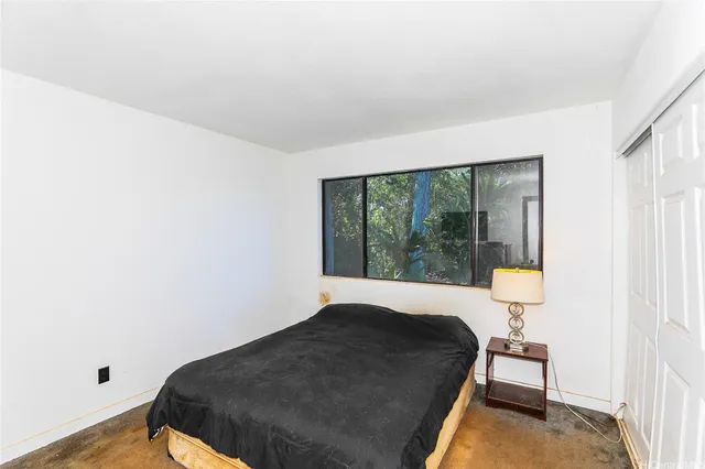 a bedroom with a bed and next to a window