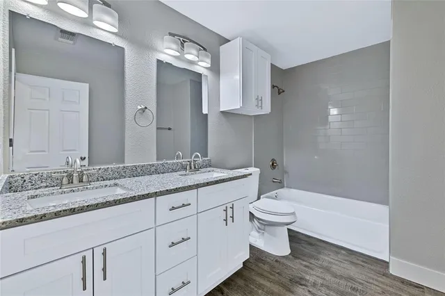 a bathroom with a granite countertop sink a toilet and a mirror