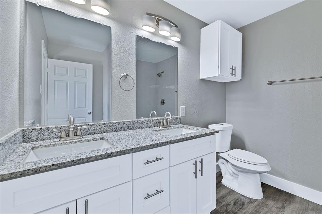 566 McCraw Lane Denison, TX 75021 - Photo 18 of 25 a bathroom with a granite countertop sink a toilet and a mirror