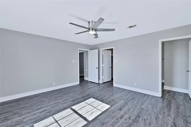 a view of an empty room and window a ceiling fan and wooden floor
