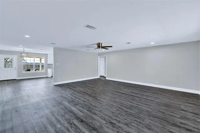 a view of empty room with wooden floor and window