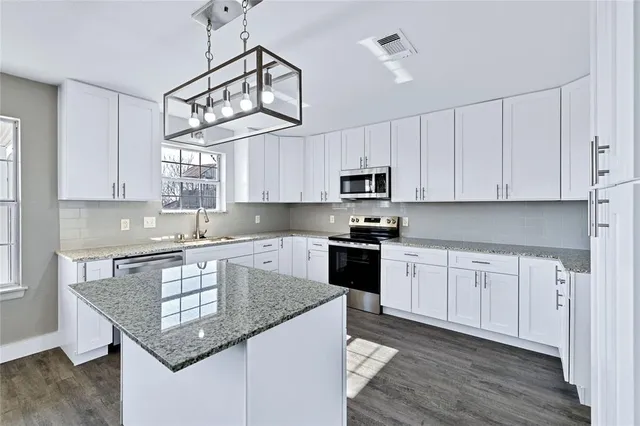a kitchen with kitchen island granite countertop a sink cabinets stainless steel appliances and a counter space