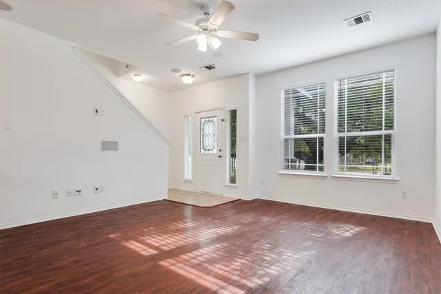 a view of an empty room with a window and wooden floor