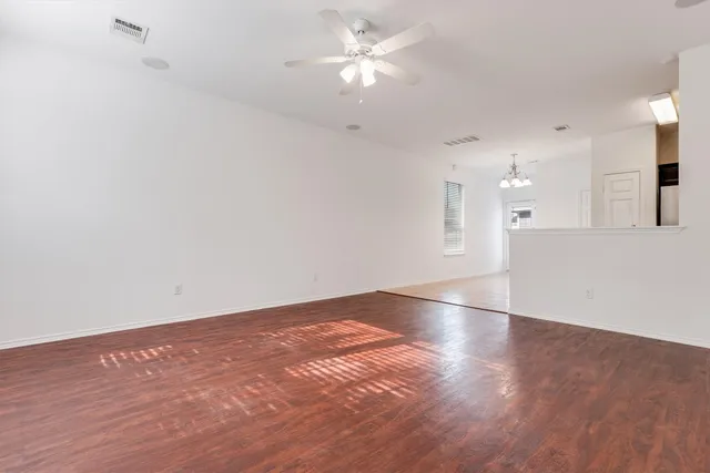 an empty room with fan and kitchen view