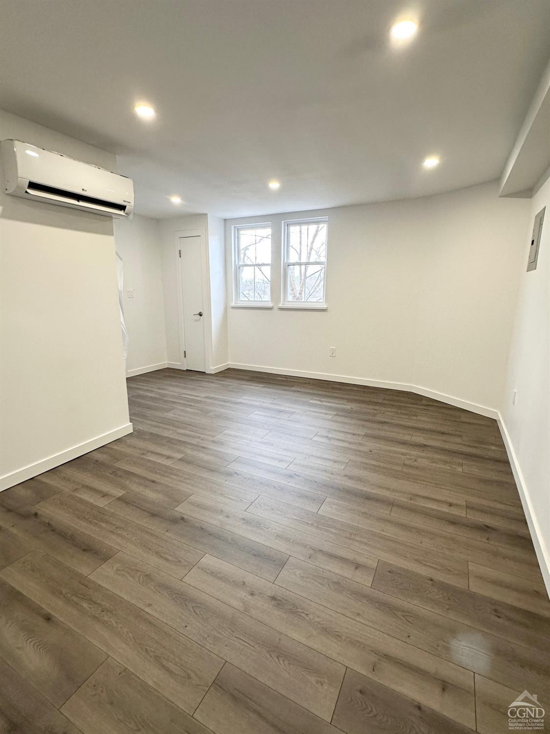 473 Main Street, Unit 1 Catskill, NY 12414 - Photo 3 of 11 an empty room with wooden floor and windows