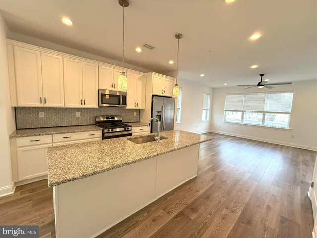 a kitchen with stainless steel appliances granite countertop white cabinets and a stove top oven