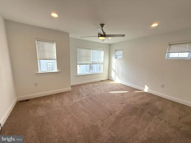 en empty room with windows and ceiling fan