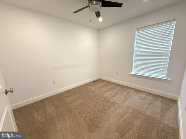 an empty room with a window and a fan