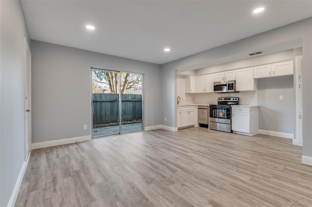 5033 Cedar Springs Road, Unit 103 Dallas, TX 75235 - Photo 4 of 12 a view of empty room with wooden floor and kitchen