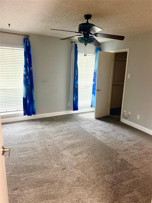 14333 Preston Road, Unit 806 Dallas, TX 75254 - Photo 10 of 17 Textured carpeting, two windows with horizontal blinds, overhead ceiling fan with lighting, and a walk-in closet
