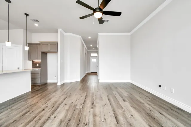 a view of a room with wooden floor and a ceiling fan