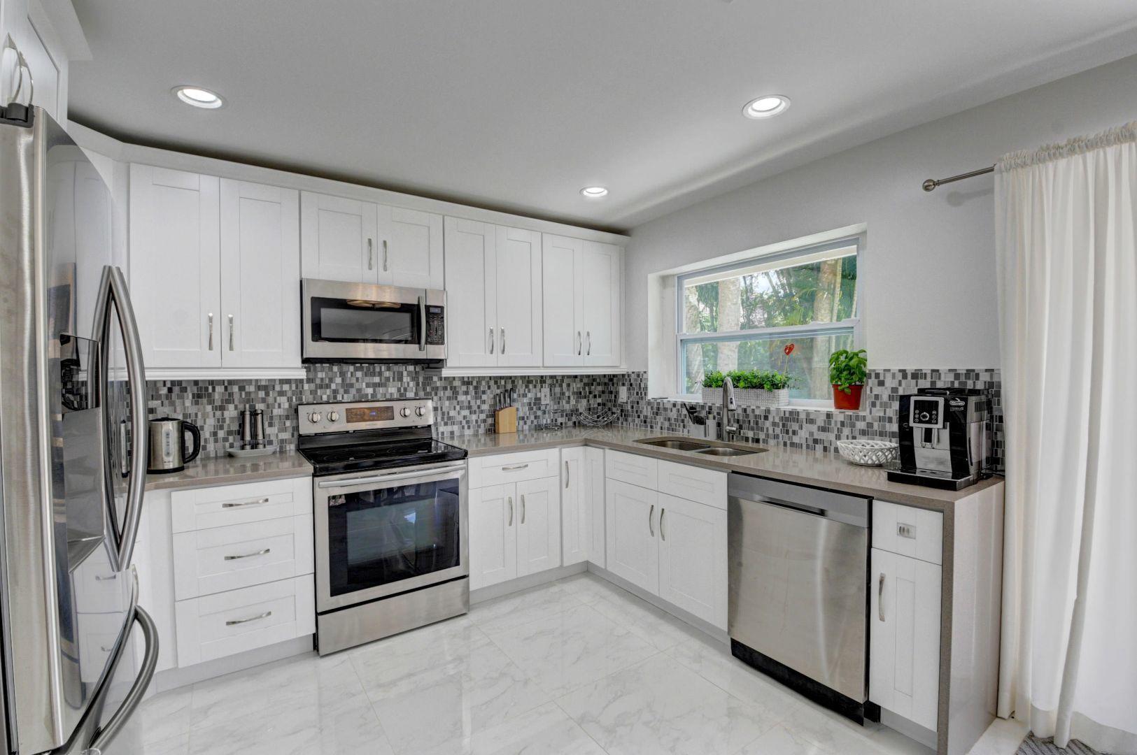 2157 Northwest 52nd Street Boca Raton, FL 33496 - Photo 12 of 27 a kitchen with white cabinets sink and stainless steel appliances