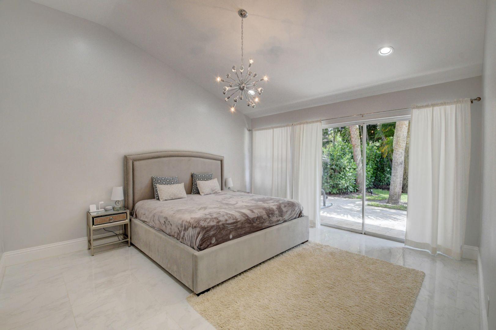 2157 Northwest 52nd Street Boca Raton, FL 33496 - Photo 15 of 27 a bedroom with a large bed and a chandelier