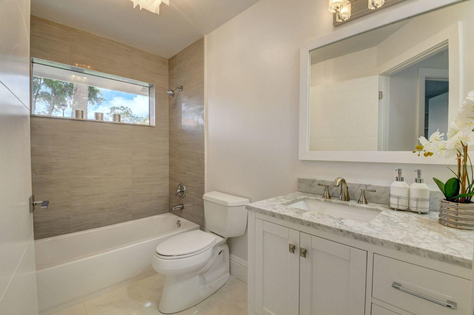 2157 Northwest 52nd Street Boca Raton, FL 33496 - Photo 20 of 27 a bathroom with a granite countertop sink toilet a large mirror a bathtub and shower