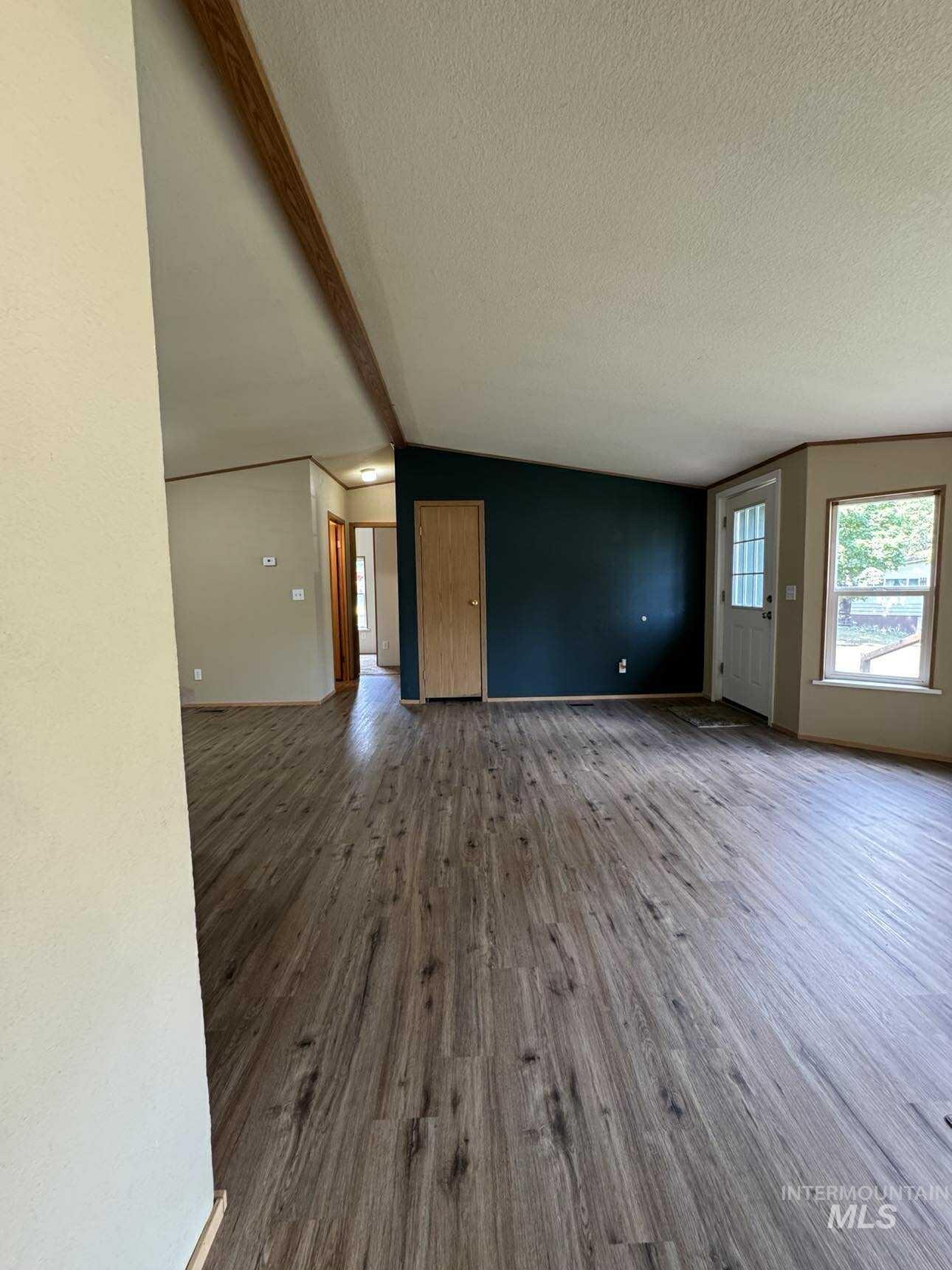 174 Elmwood Loop, Unit 7 Lenore, ID 83541 - Photo 2 of 11 Unfurnished living room featuring beamed ceiling, wood finished floors, and a textured ceiling