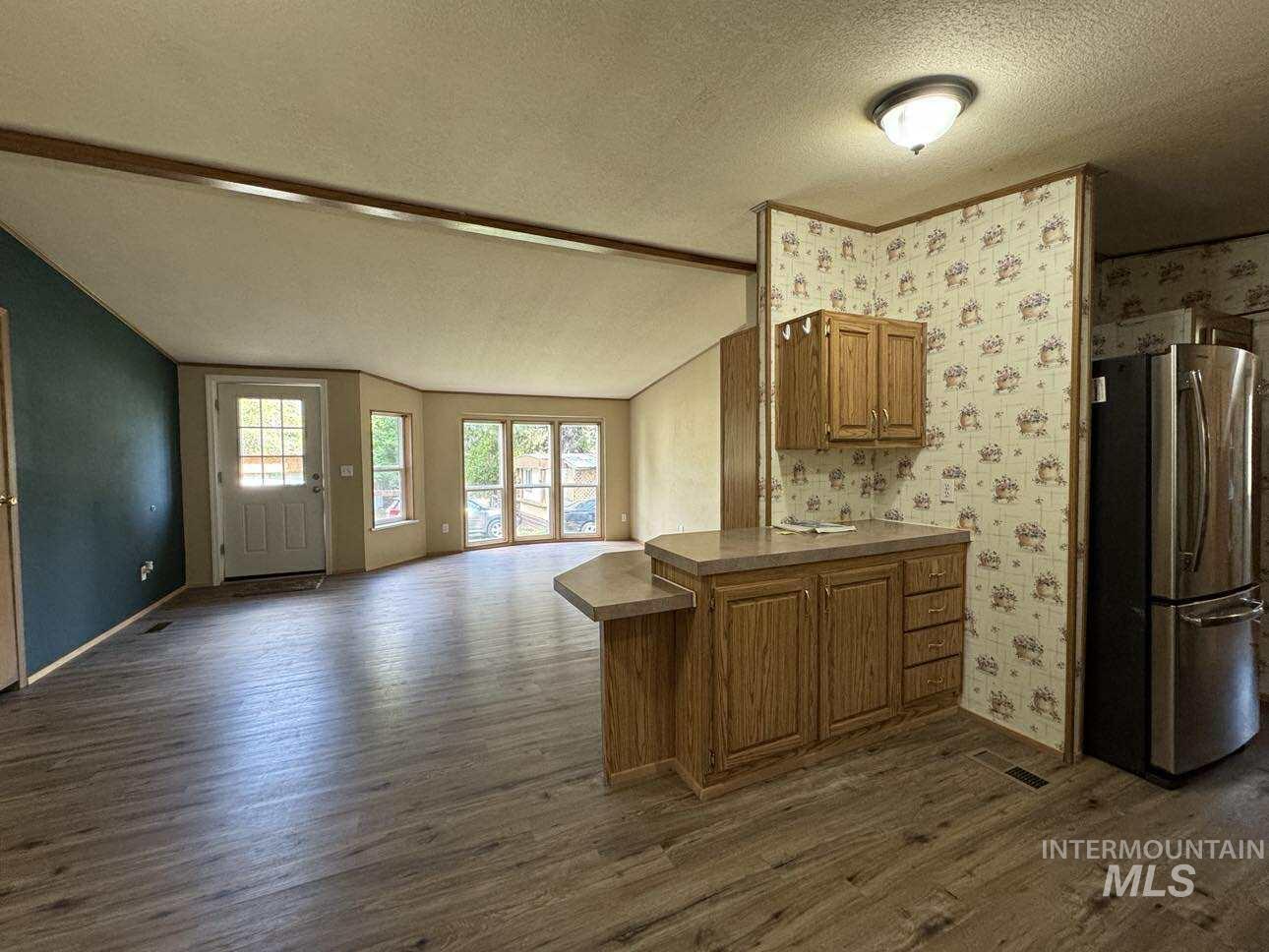 174 Elmwood Loop, Unit 7 Lenore, ID 83541 - Photo 10 of 11 Kitchen with freestanding refrigerator, wood finish cabinets, open floor plan, dark wood-type flooring, and a peninsula