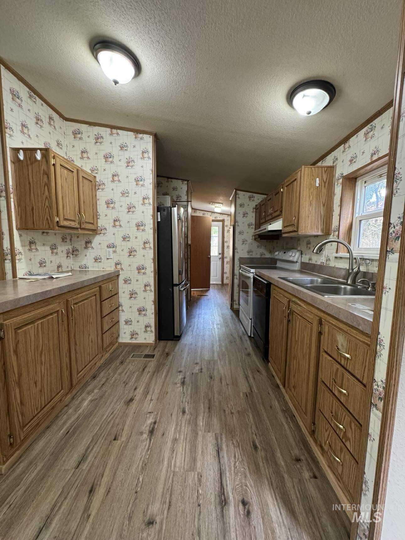 174 Elmwood Loop, Unit 7 Lenore, ID 83541 - Photo 3 of 11 Kitchen with wallpapered walls, a textured ceiling, dark wood finished floors, electric stove, and freestanding refrigerator