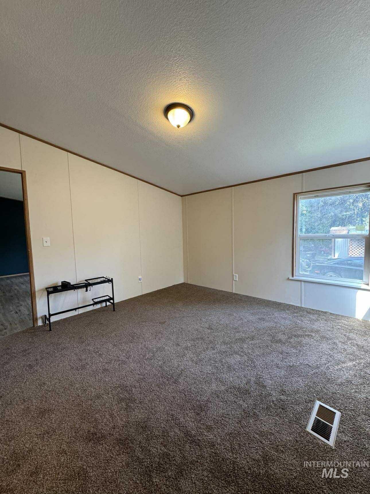 174 Elmwood Loop, Unit 7 Lenore, ID 83541 - Photo 4 of 11 Carpeted spare room with a textured ceiling and a decorative wall