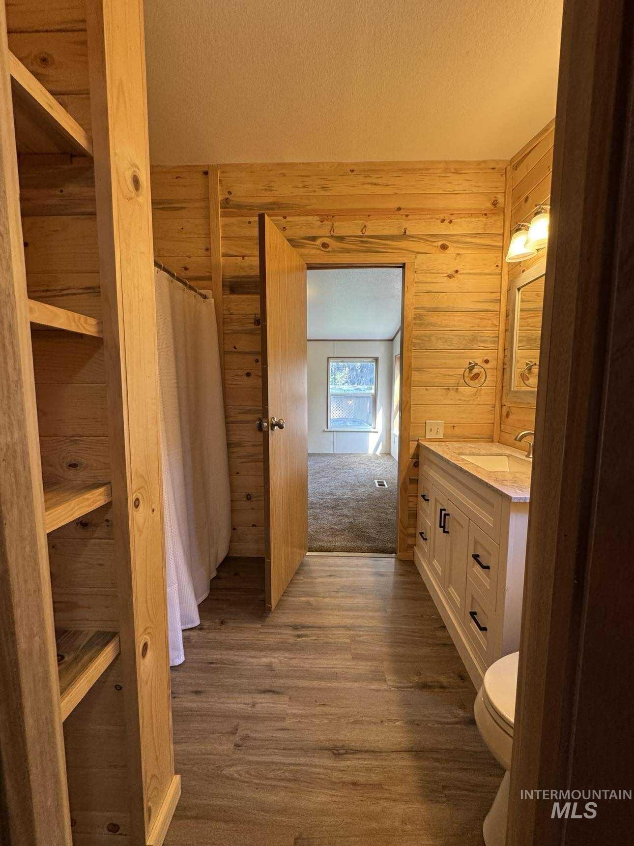 174 Elmwood Loop, Unit 7 Lenore, ID 83541 - Photo 5 of 11 Full bathroom with vanity, a textured ceiling, curtained shower, dark wood-style flooring, and wood walls
