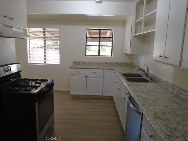 a kitchen with granite countertop a sink stove and cabinets